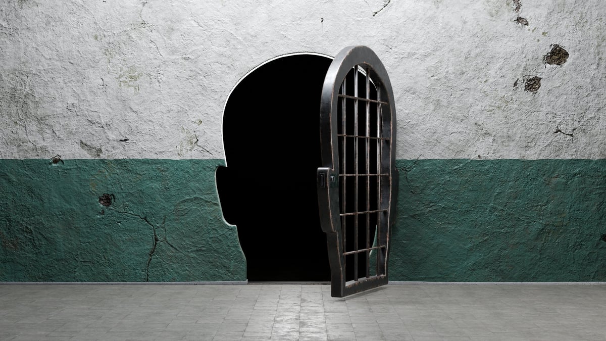 Human head shaped prison door open in a cracked wall symbolizing liberation from confinement