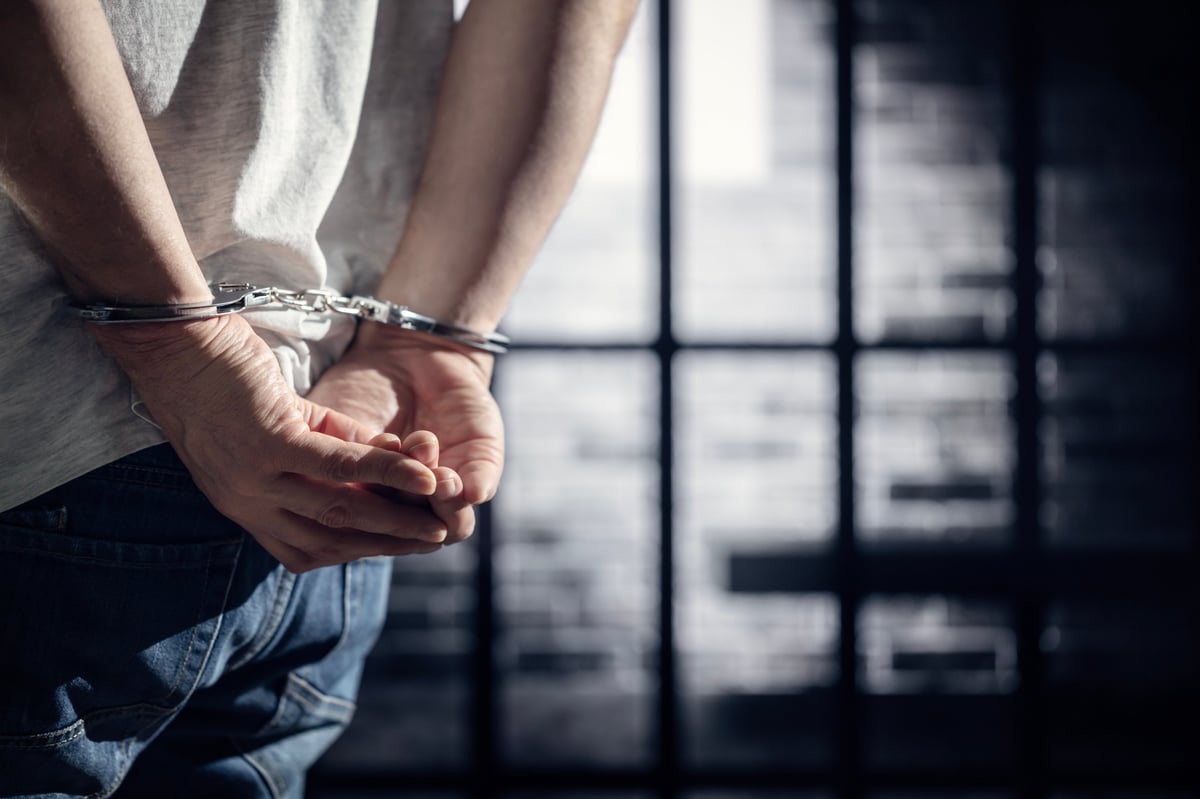 Arrested man in handcuffs in prison