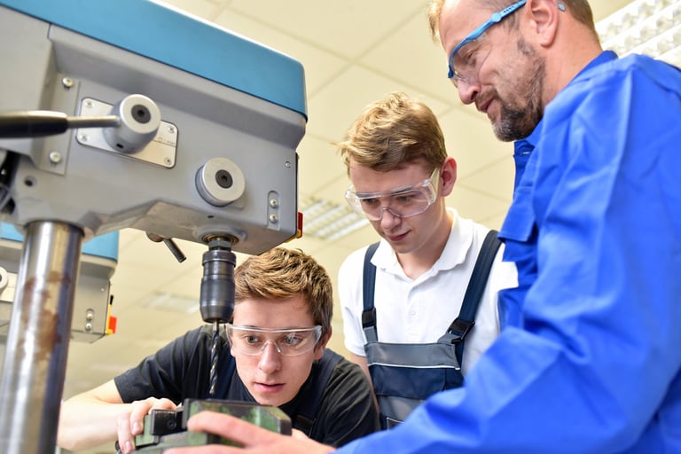 trainer and apprentice in technical vocational training at a drilling machine